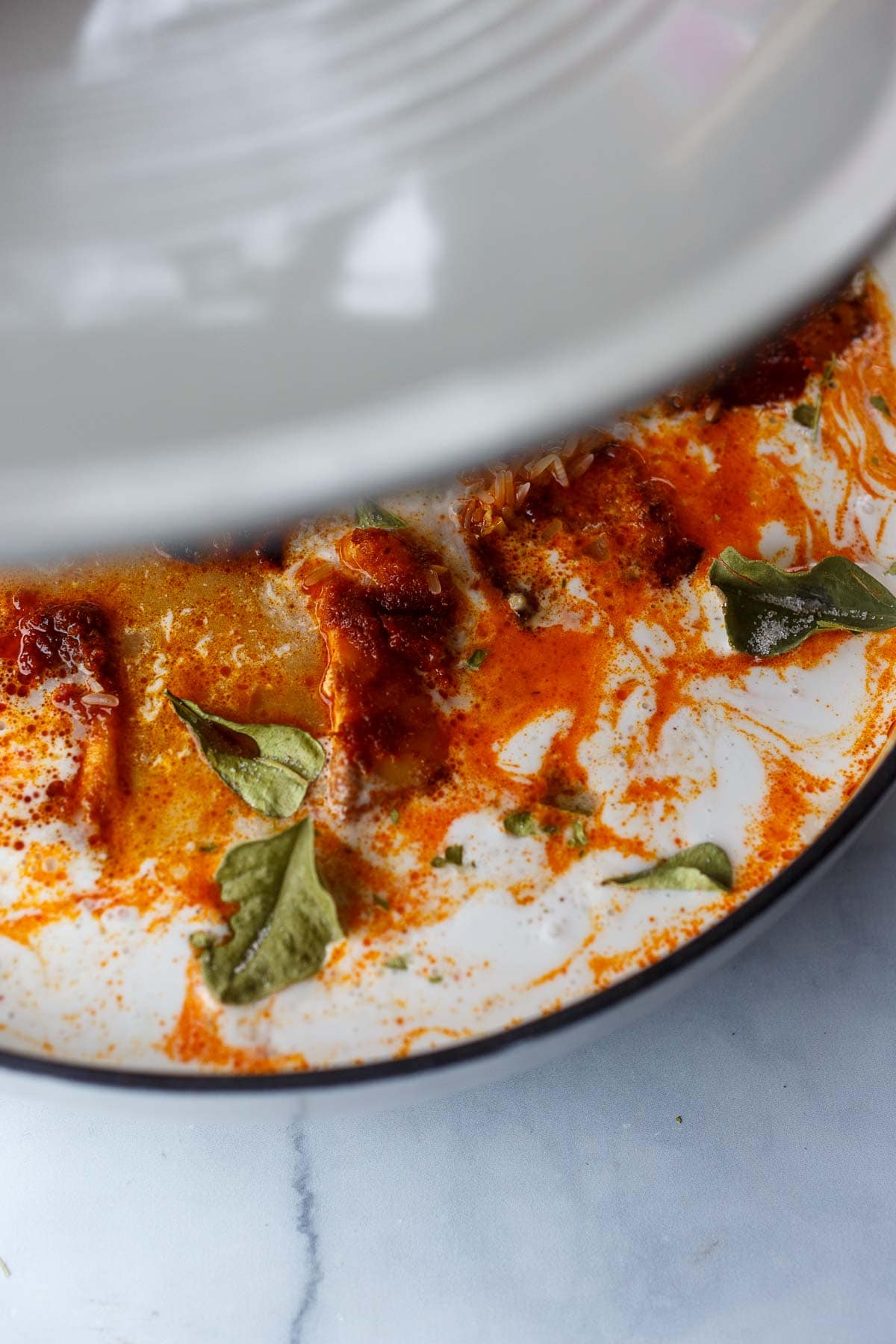 adding lid to dutch oven with baked thai chicken in rice and coconut milk.