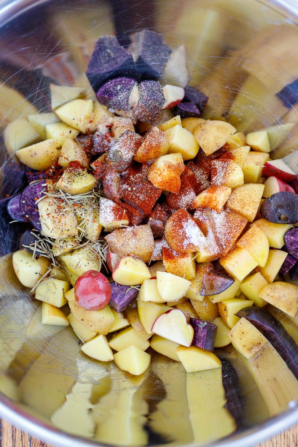 chopped potatoes in large mixing bowl with spices and dried herbs.