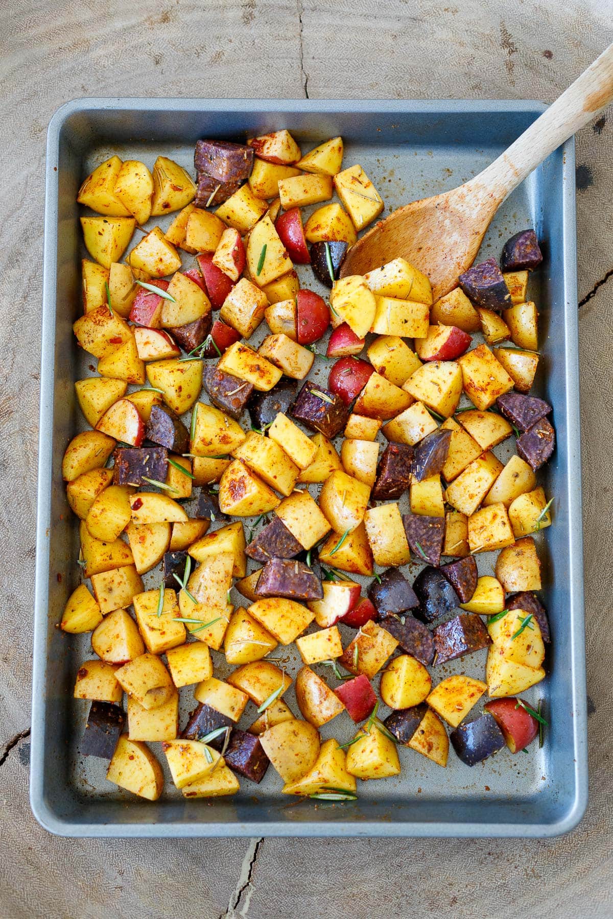 seasoned chopped potatoes spread out on sheet pan.