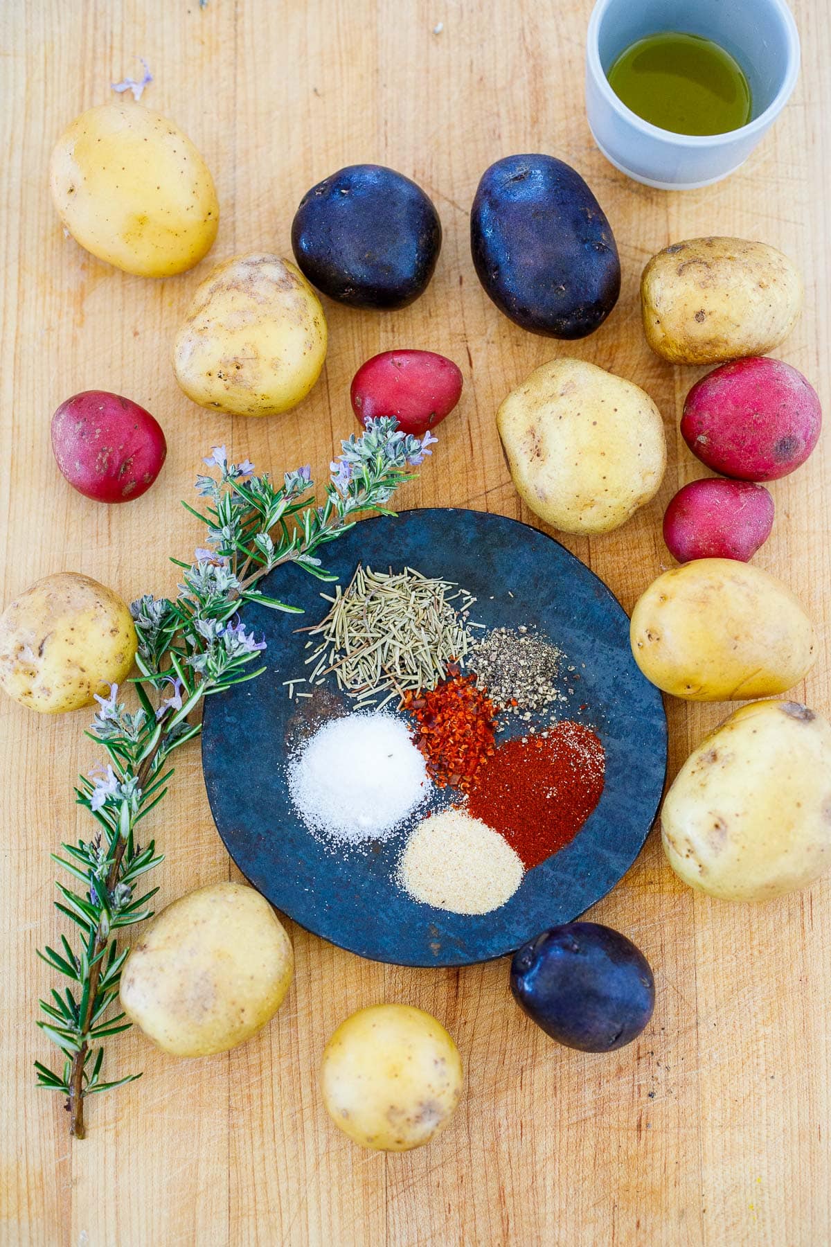 ingredients for breakfast potatoes- medley of baby potatoes, fresh rosemary, dish with assorted spices and salt.