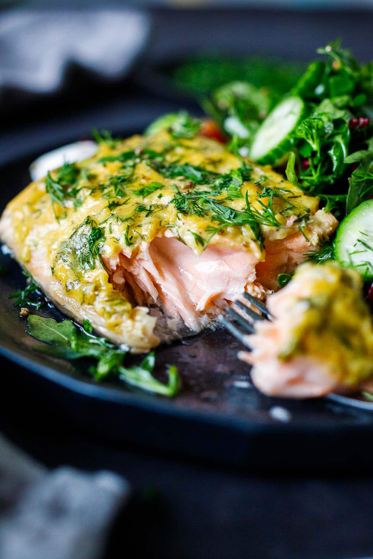 baked dijon salmon on plate, showing flaky interior, topped with fresh herbs and served beside green salad.
