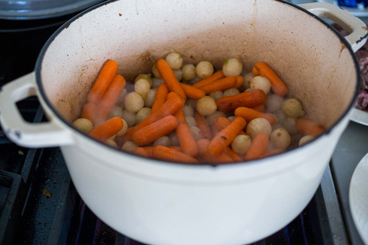 onions and carrots cooking in a dutch oven. 