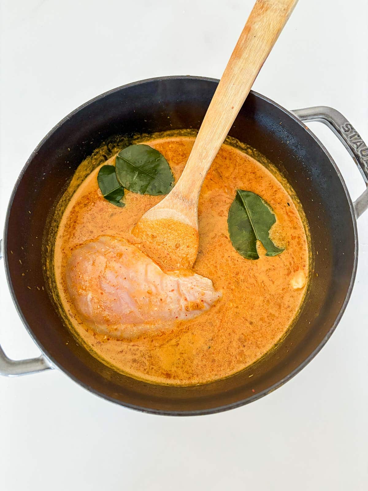Adding raw chicken breast to the broth to simmer and cook.