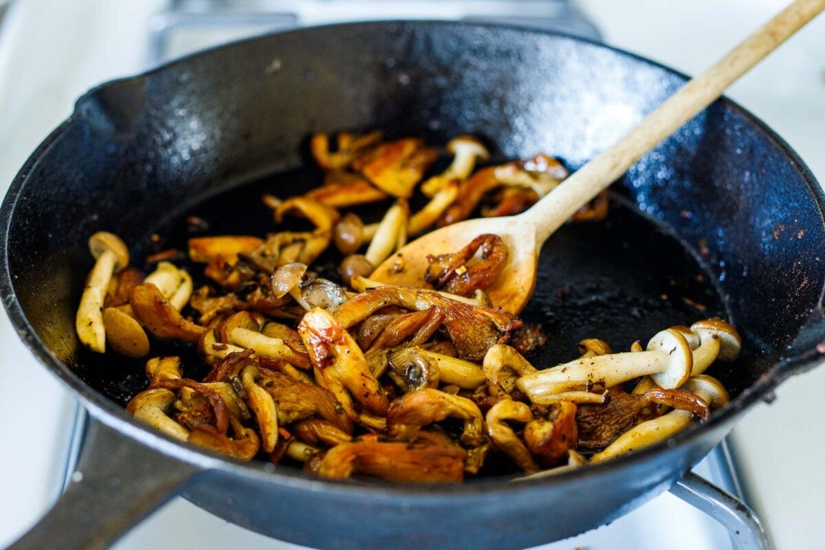 mixed mushrooms sautéing in cast iron skillet.