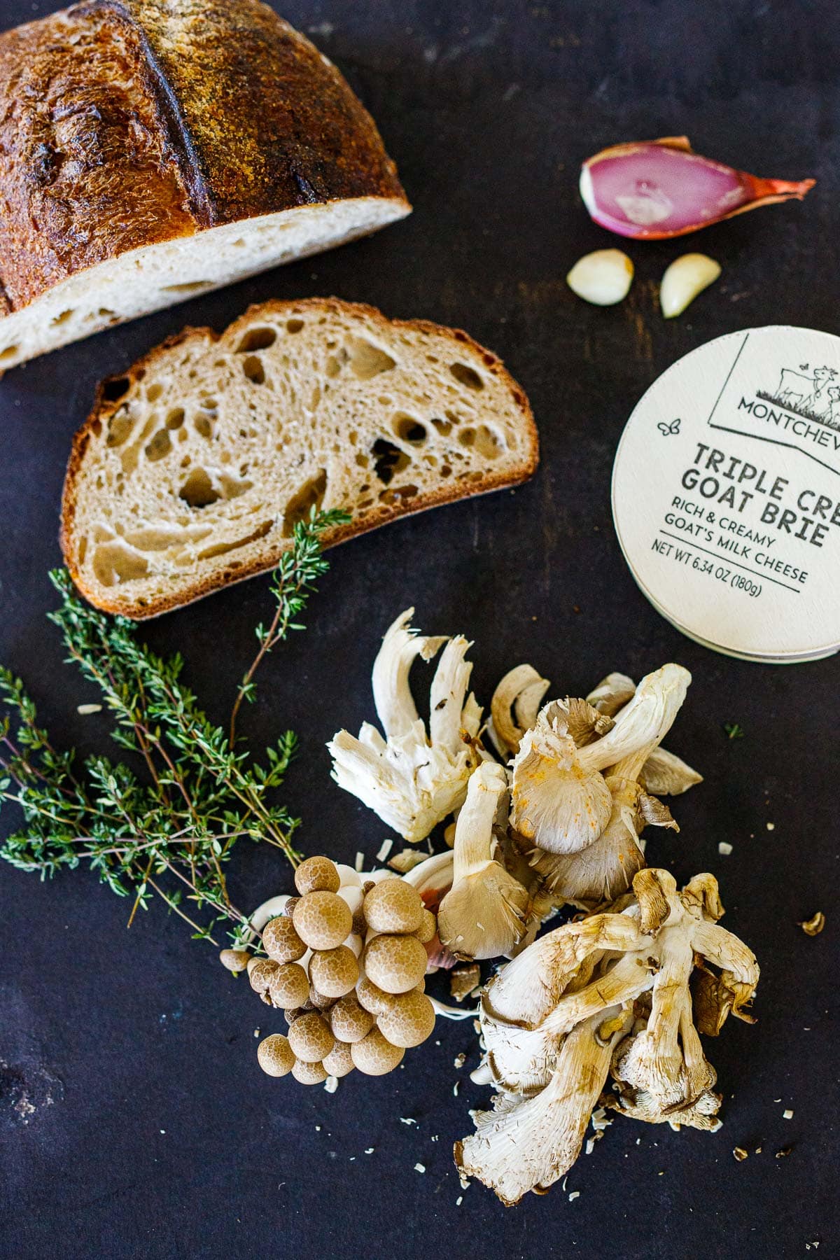ingredients for mushroom toast - sourdough bread, shallot, garlic, goat cheese, mushrooms, thyme. 