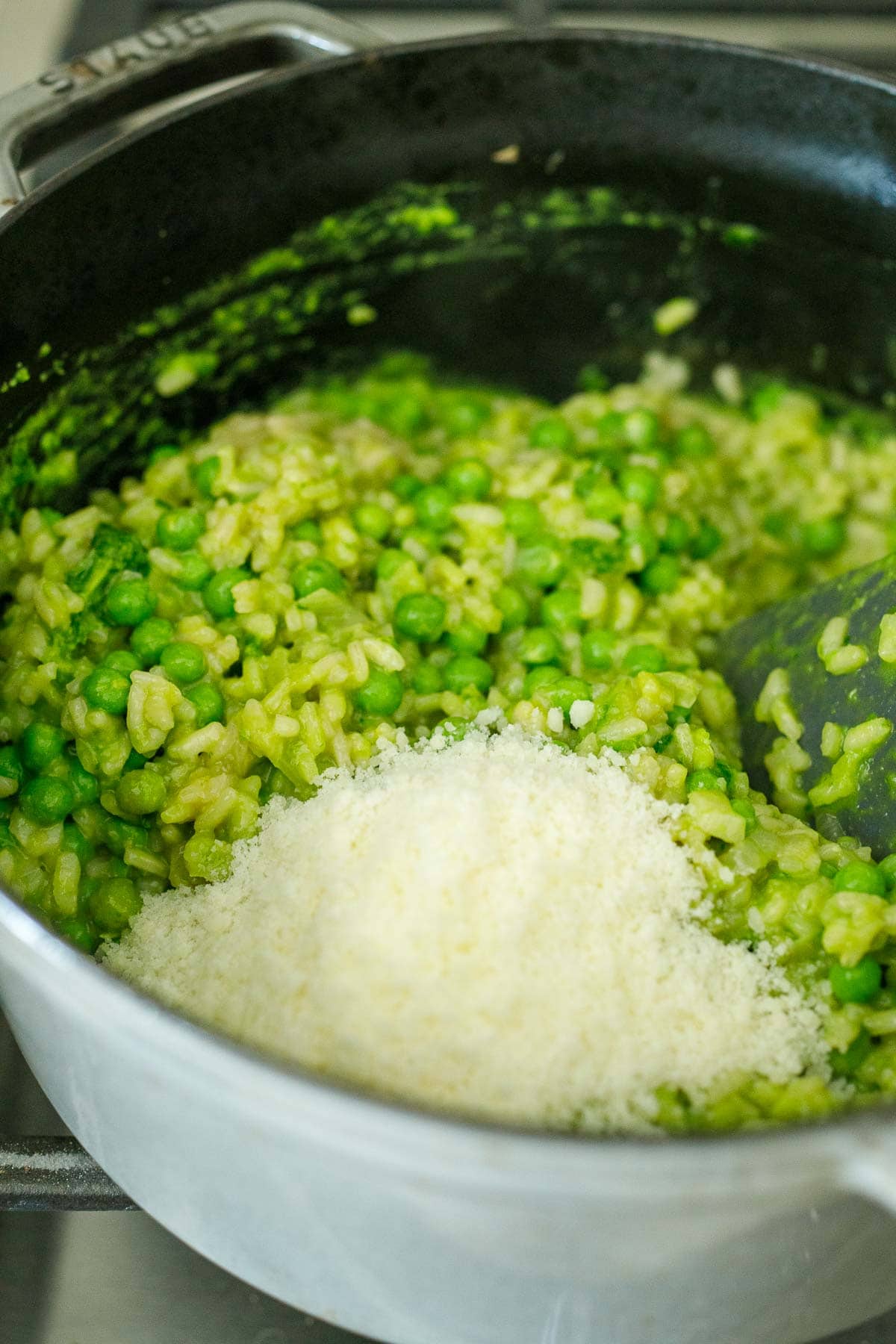 grated pecorino cheese added to pot with spring pea risotto.