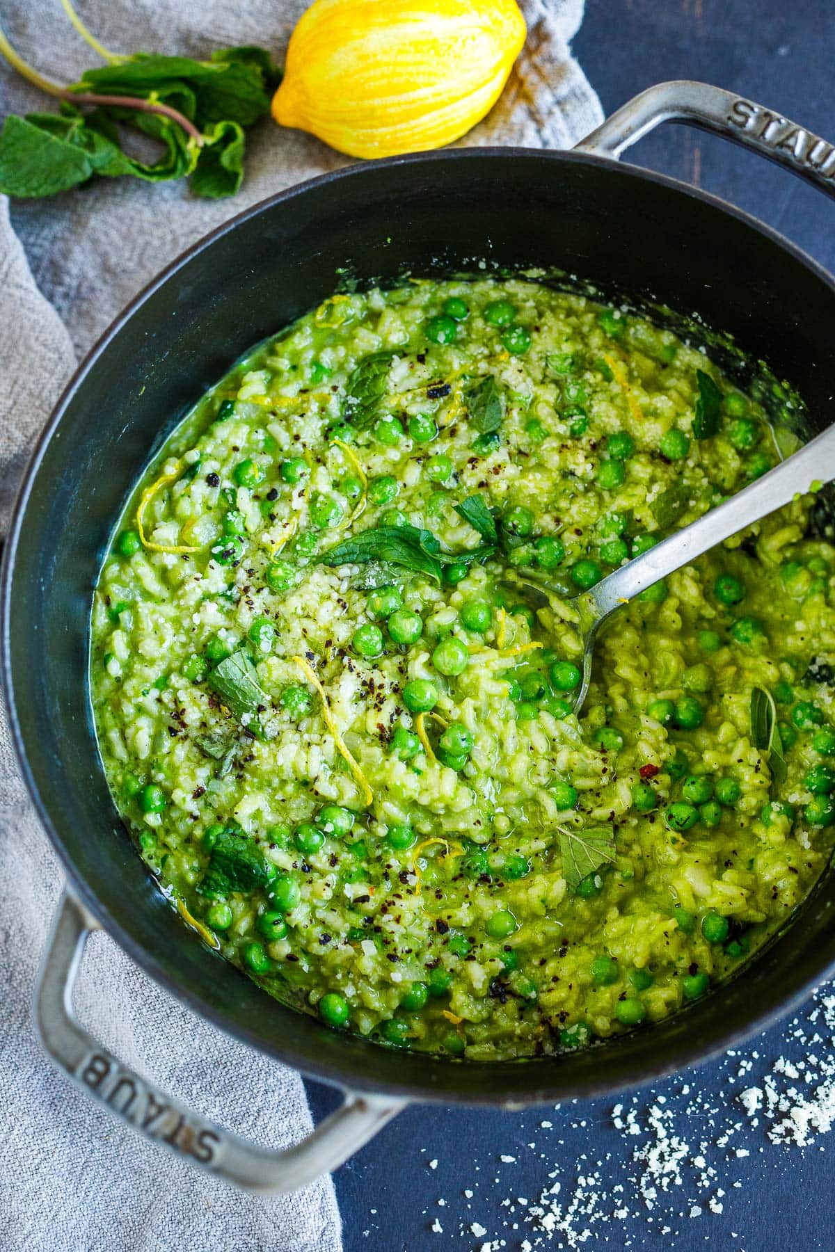 creamy, green spring pea risotto in pot with peas, mint, and lemon zest.