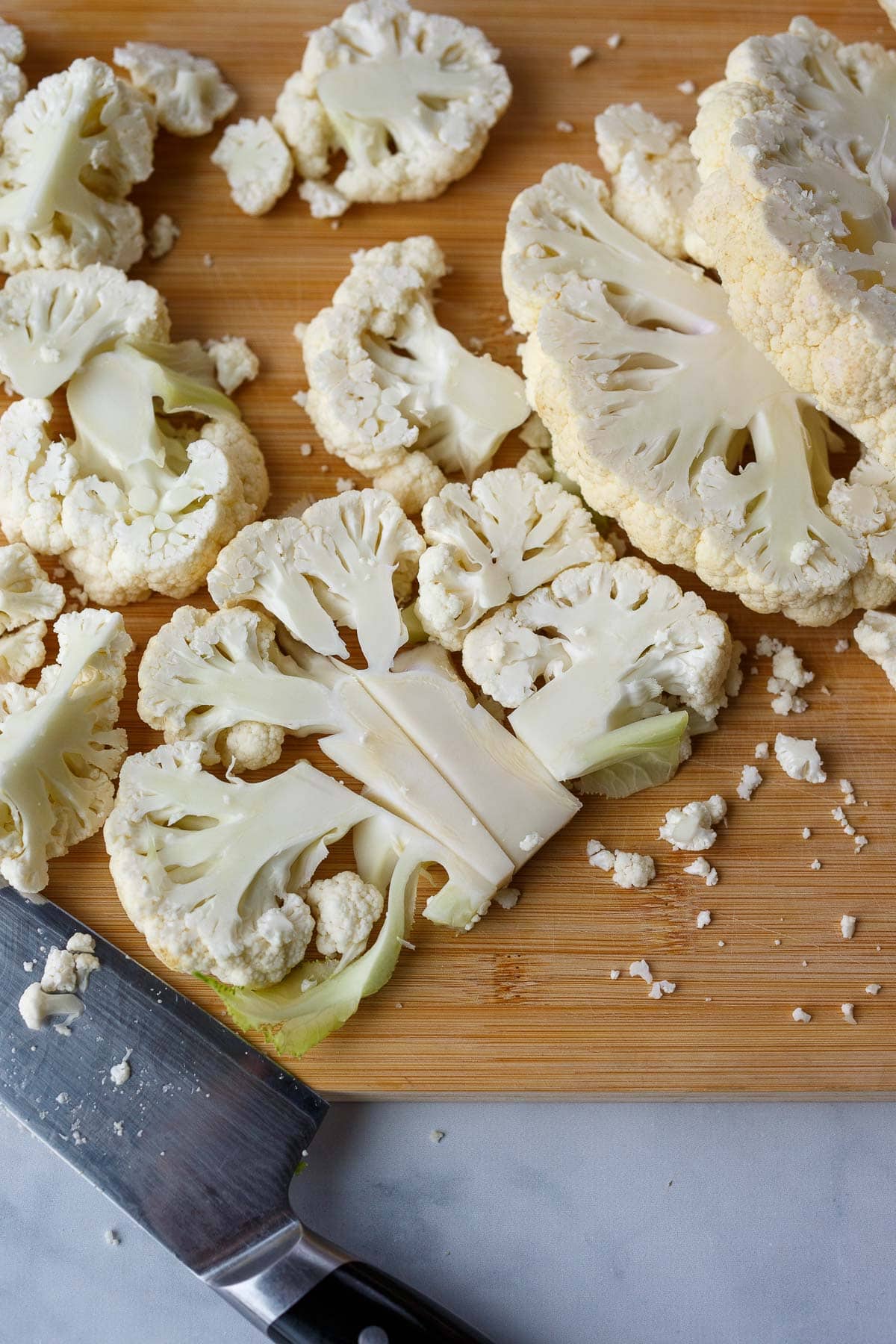 how to cut cauliflower for chili crisp cauliflower recipe- knife and cutting board with cauliflower head cut into 1 inch slices.