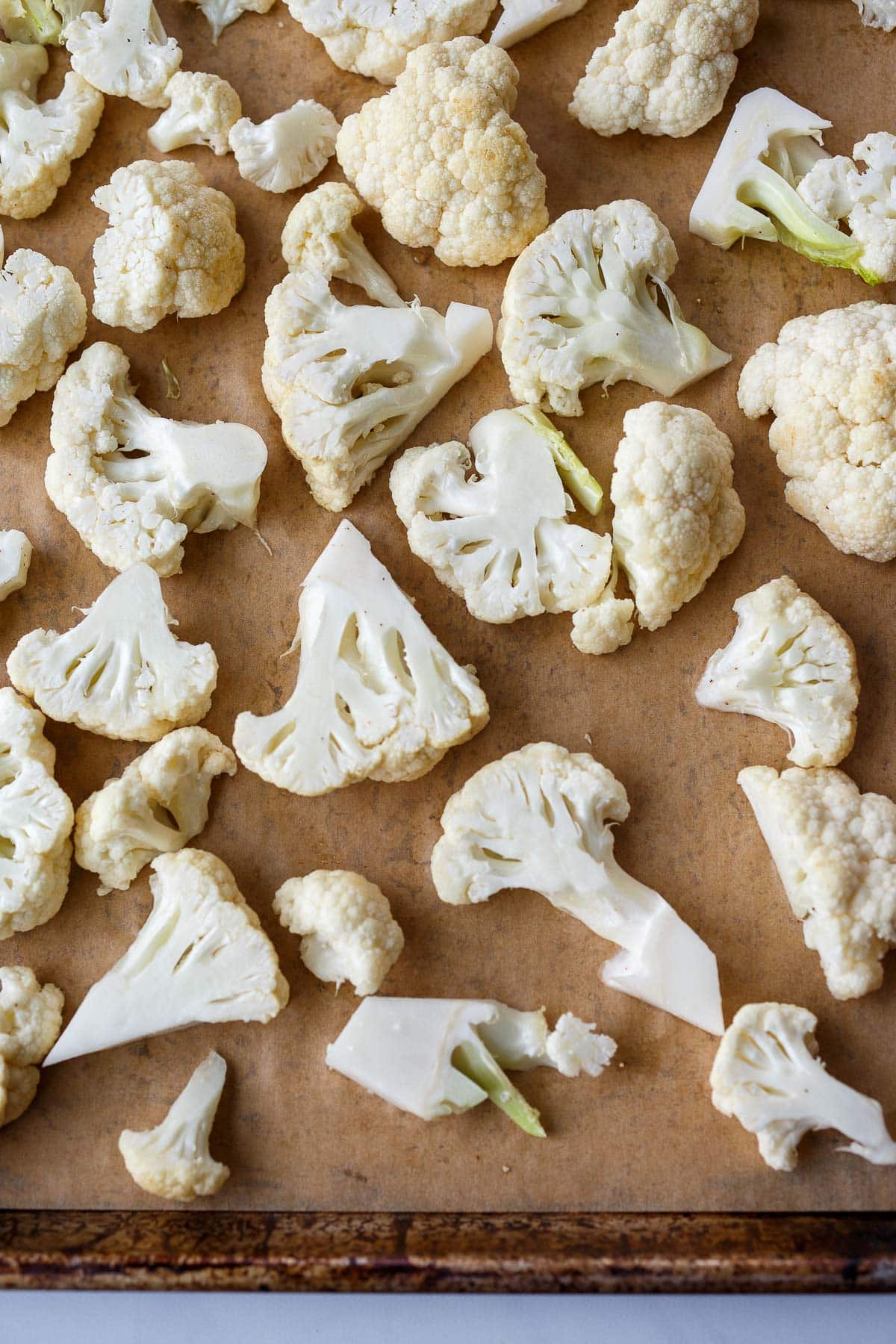 cauliflower florets spread out on parchment-lined baking sheet.