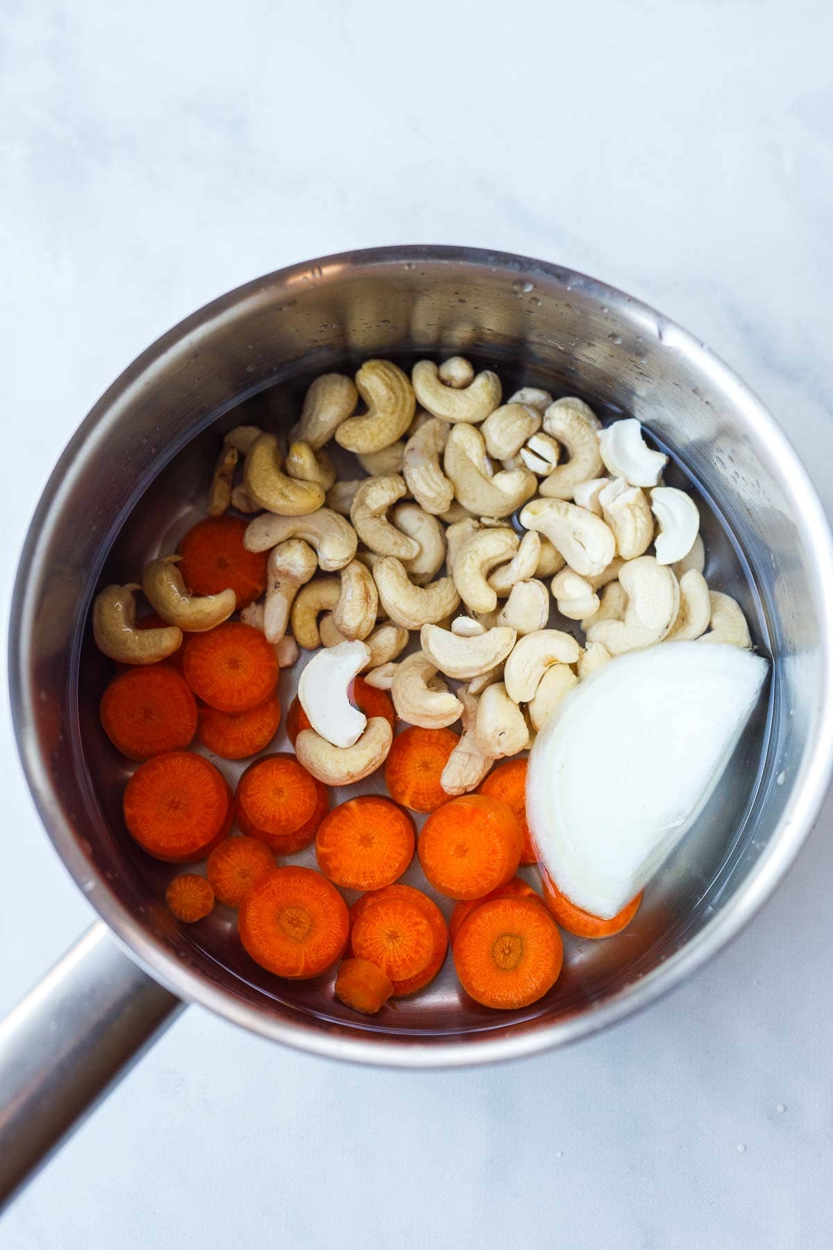 carrots, cashews, and onion in saucepan with water.