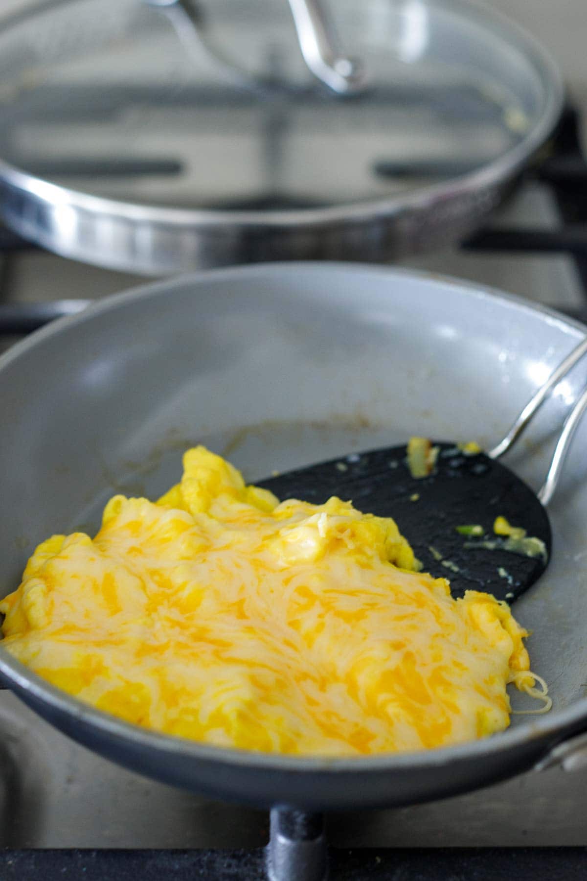 skillet with scrambled eggs and melty cheese on top.