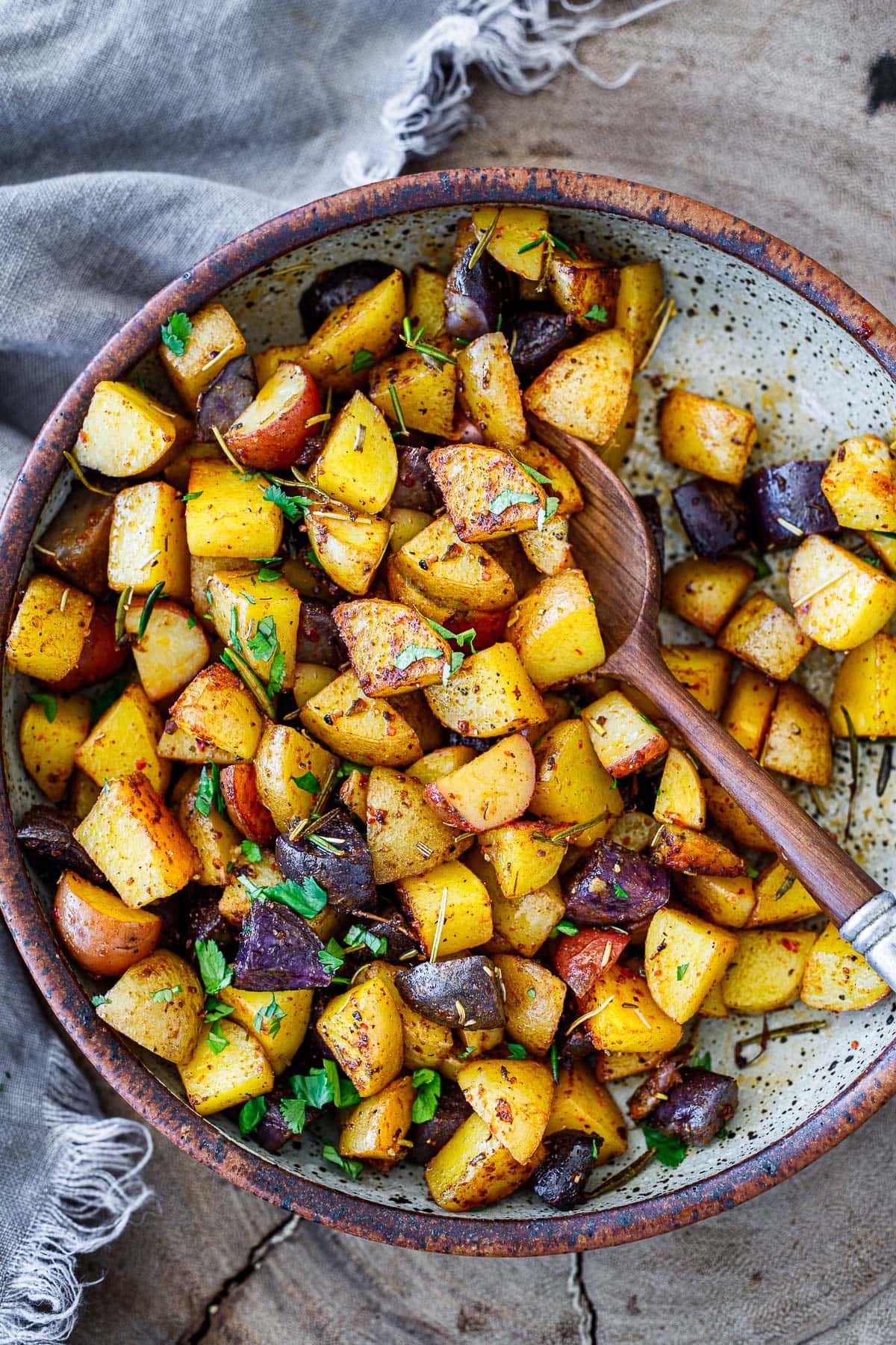 roasted breakfast potatoes in serving dish with fresh herbs sprinkled over top.