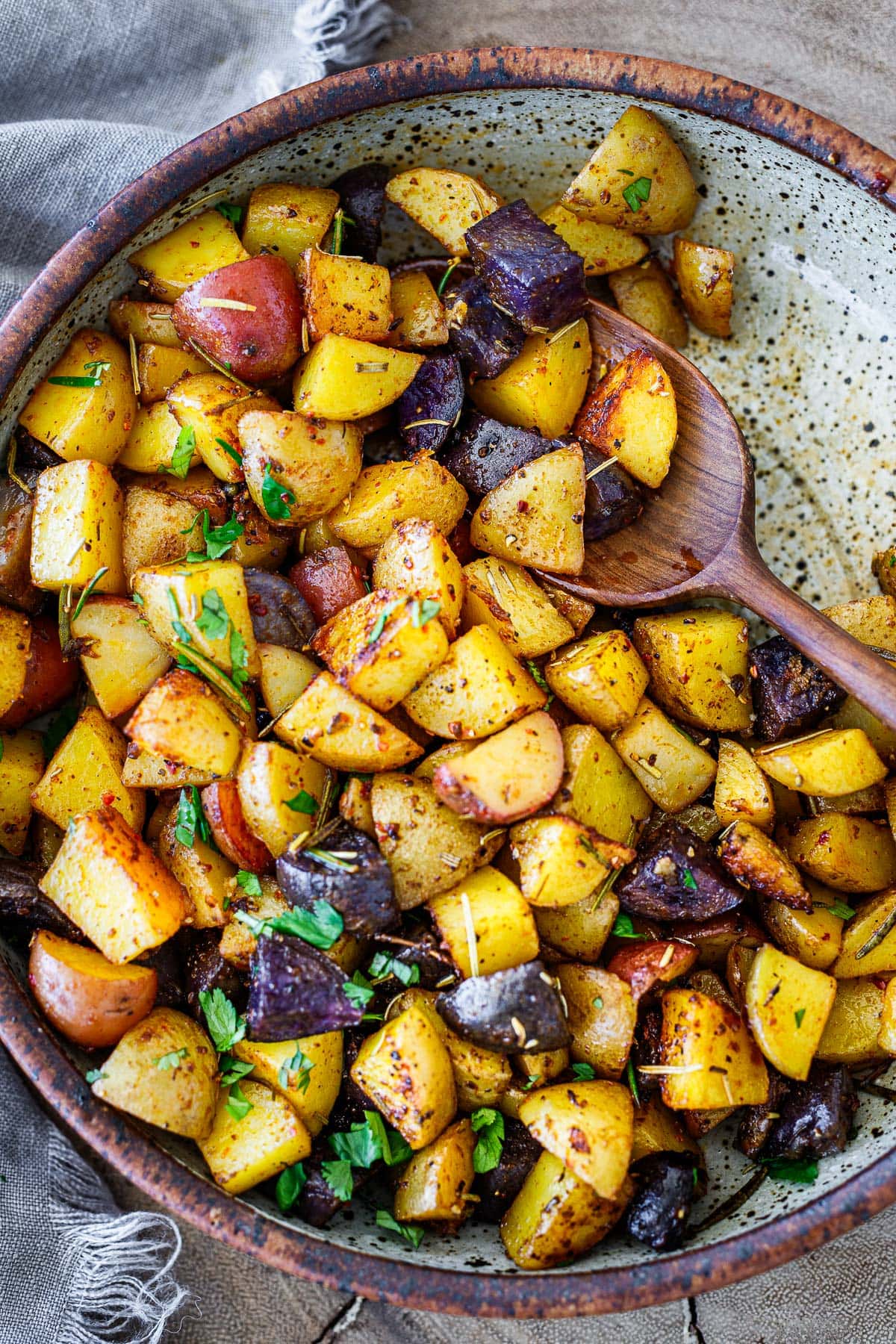 roasted rosemary breakfast  potatoes in serving dish, garnished with fresh herbs.