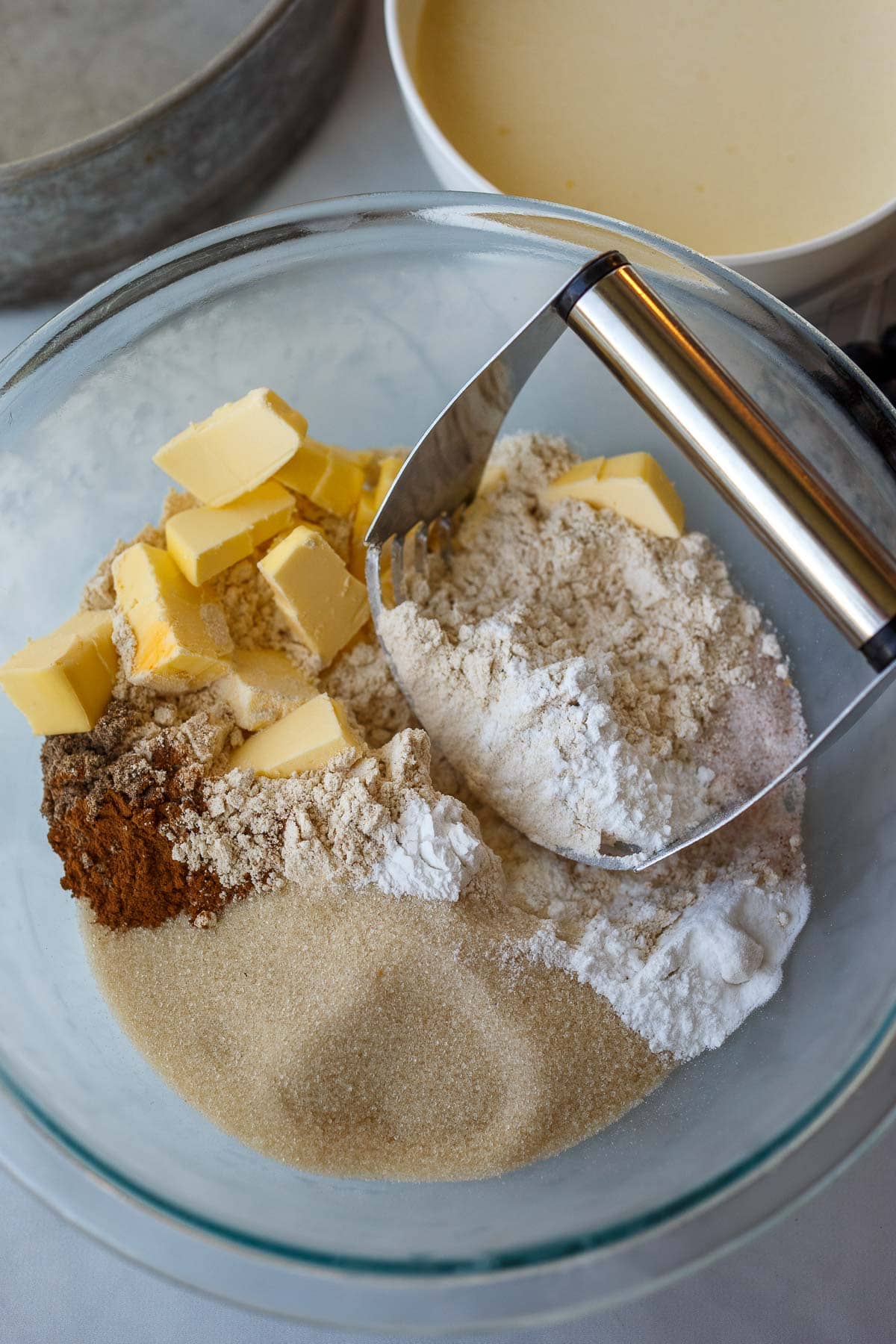 pastry cutter in mixing bowl with flour, sugar, spices, butter.