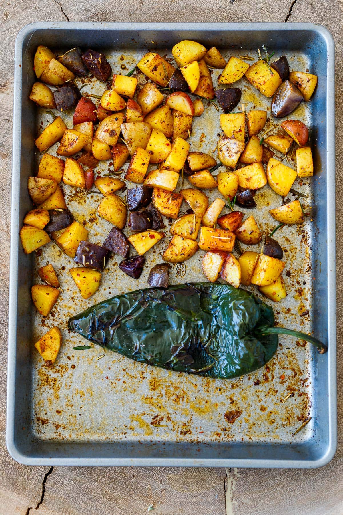 baking sheet with roasted potatoes and roasted poblano pepper.