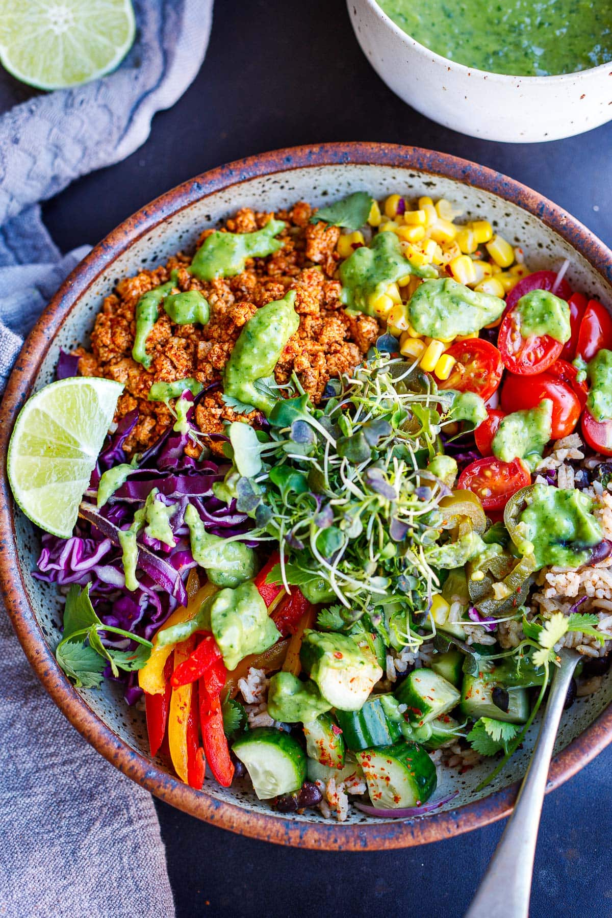 A burrito bowl with sofritas, rice, black beans, fresh veggies, lime, and avocado sauce. 
