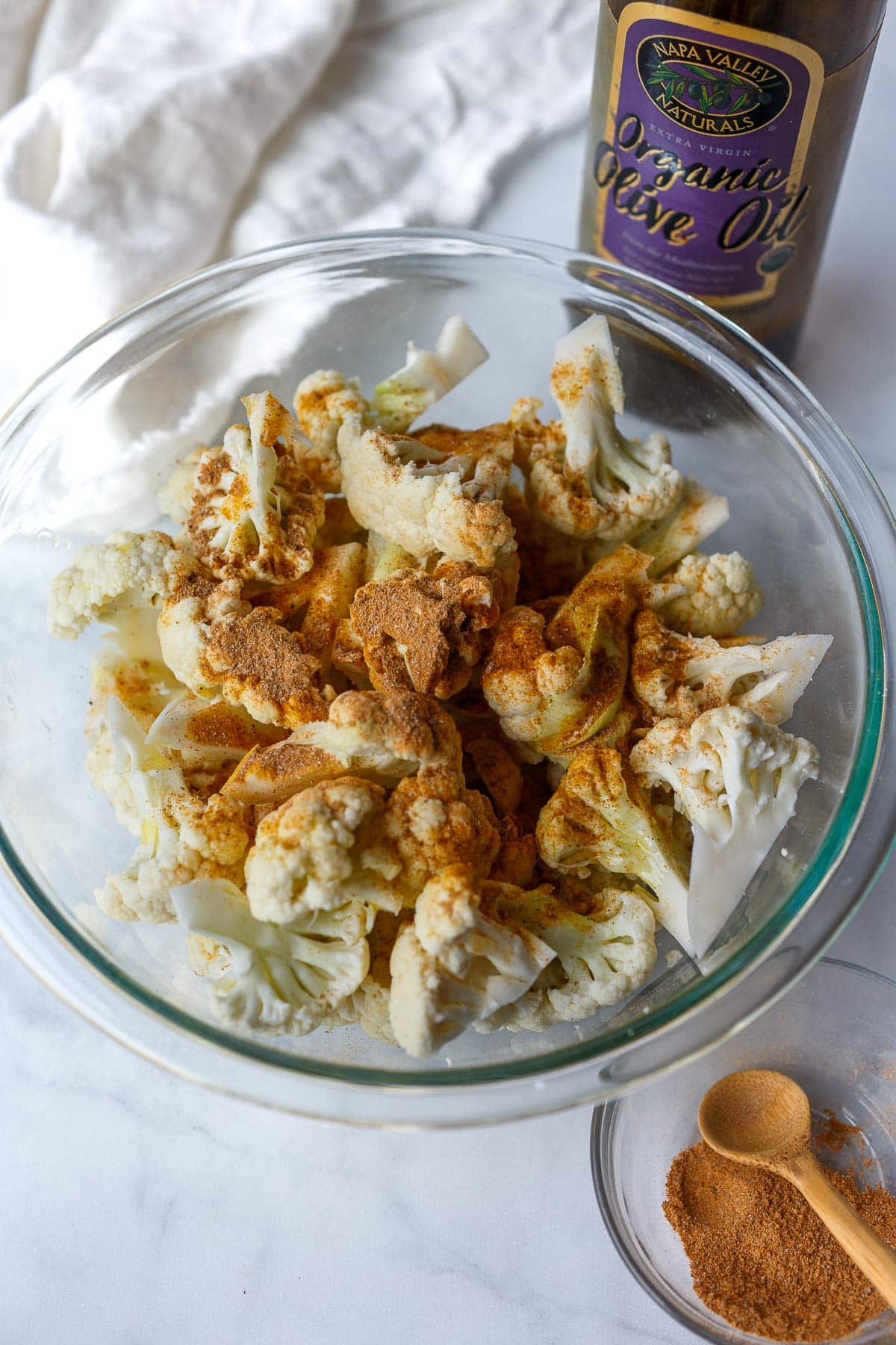 cauliflower florets with shawarma spice blend in glass bowl. 