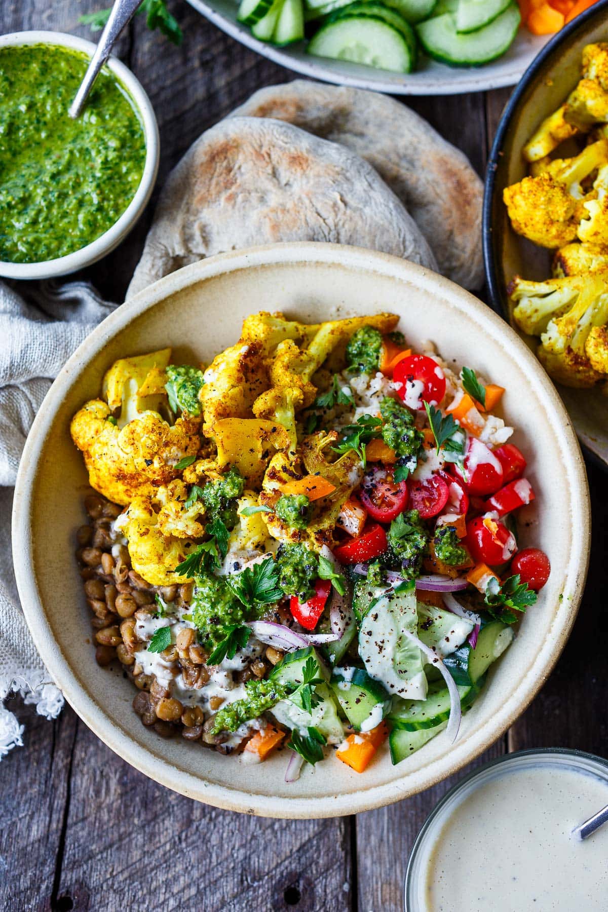 roasted cauliflower shawarma served in bowl with lentils, tomato, cucumber, onion, and zhoug.