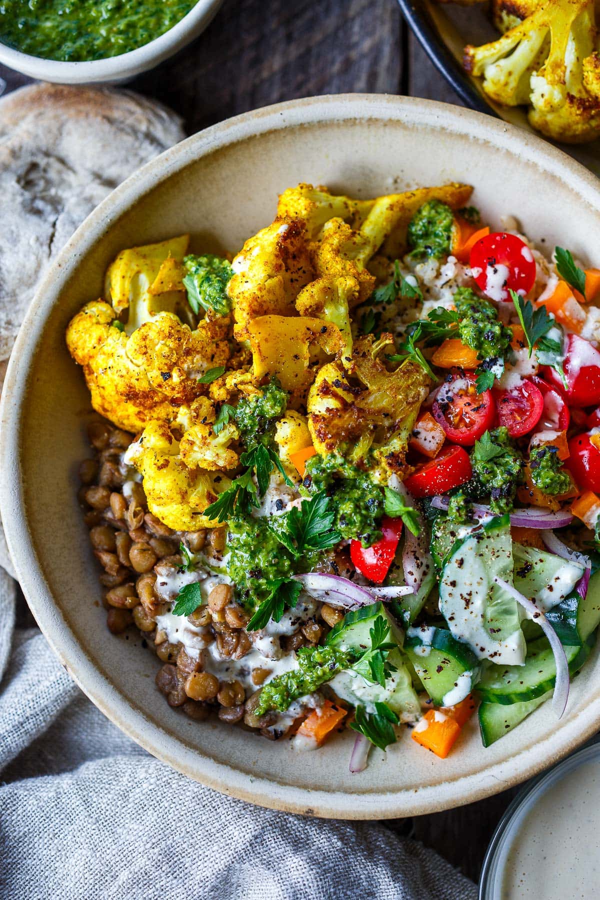 cauliflower shawarma bowl with lentils, tomatoes, cucumber, onion, zhoug, and tahini sauce.