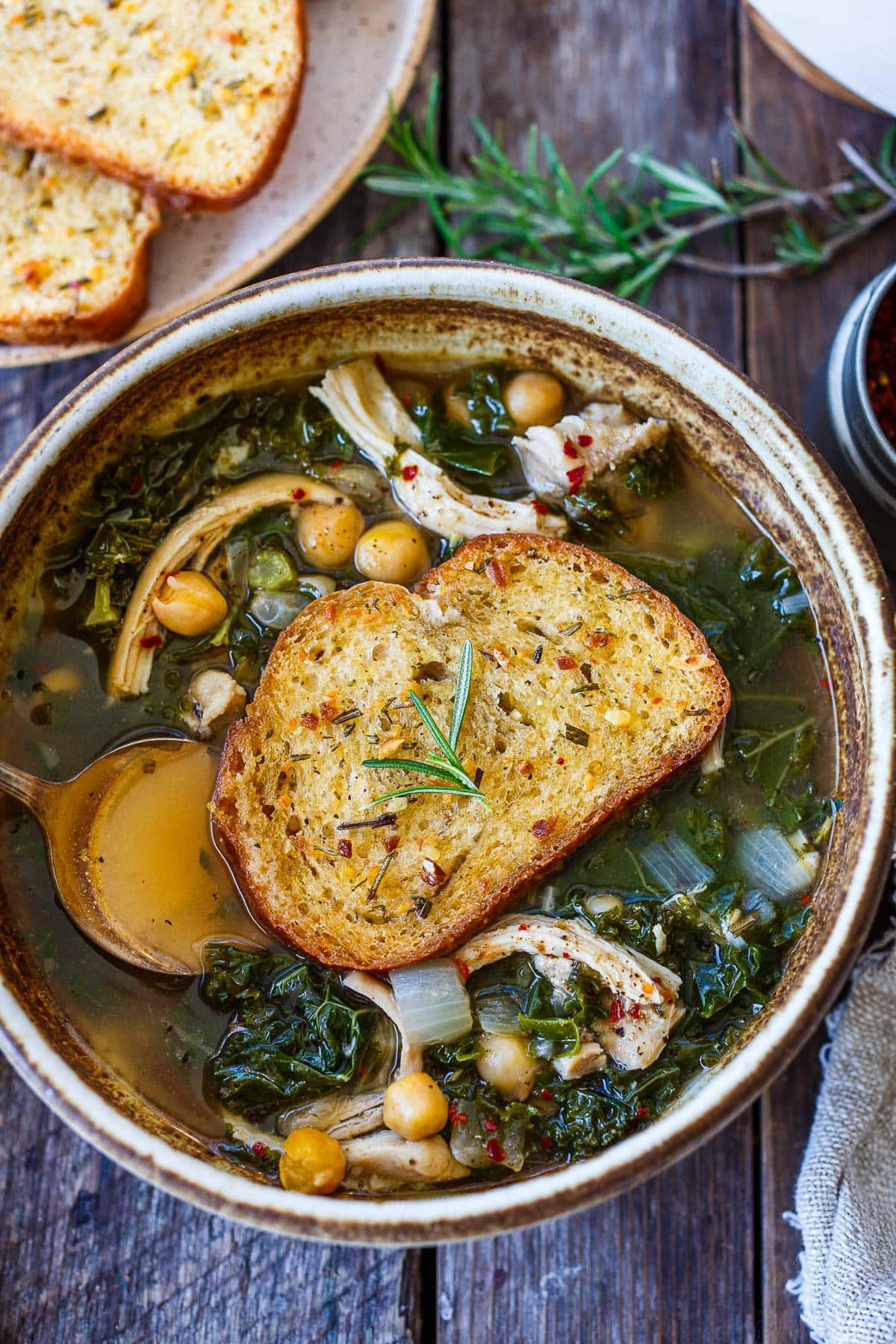 chicken and kale soup in bowl with rosemary crouton on top.