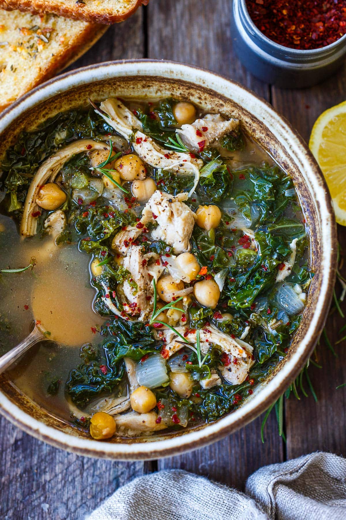 bowl of chicken and kale soup with chickpeas, chili flakes.