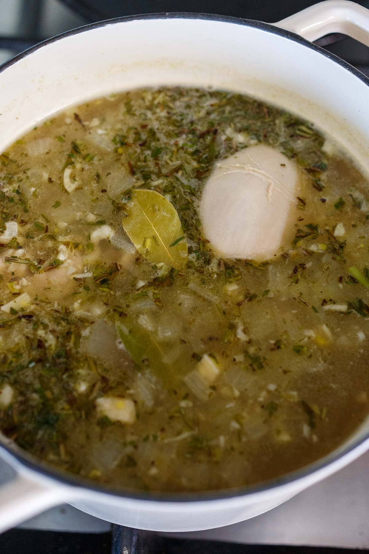 chicken thighs, bay leaf, and broth added to soup pot.