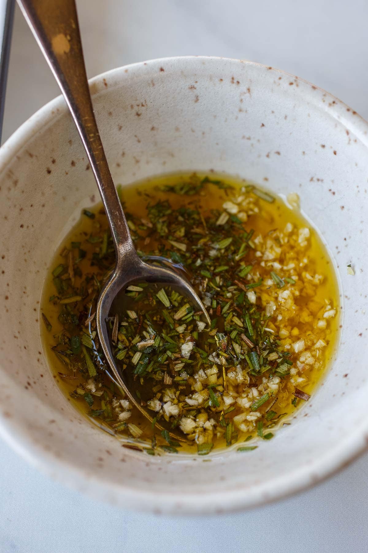 oil, rosemary, and garlic in small bowl with spoon.
