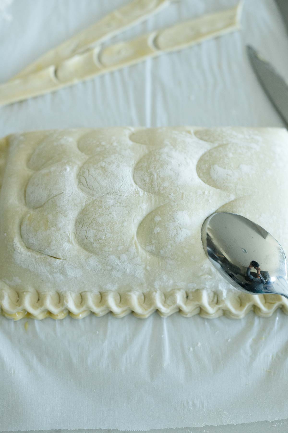 using a spoon to create fish scales on the top of the puff pastry.