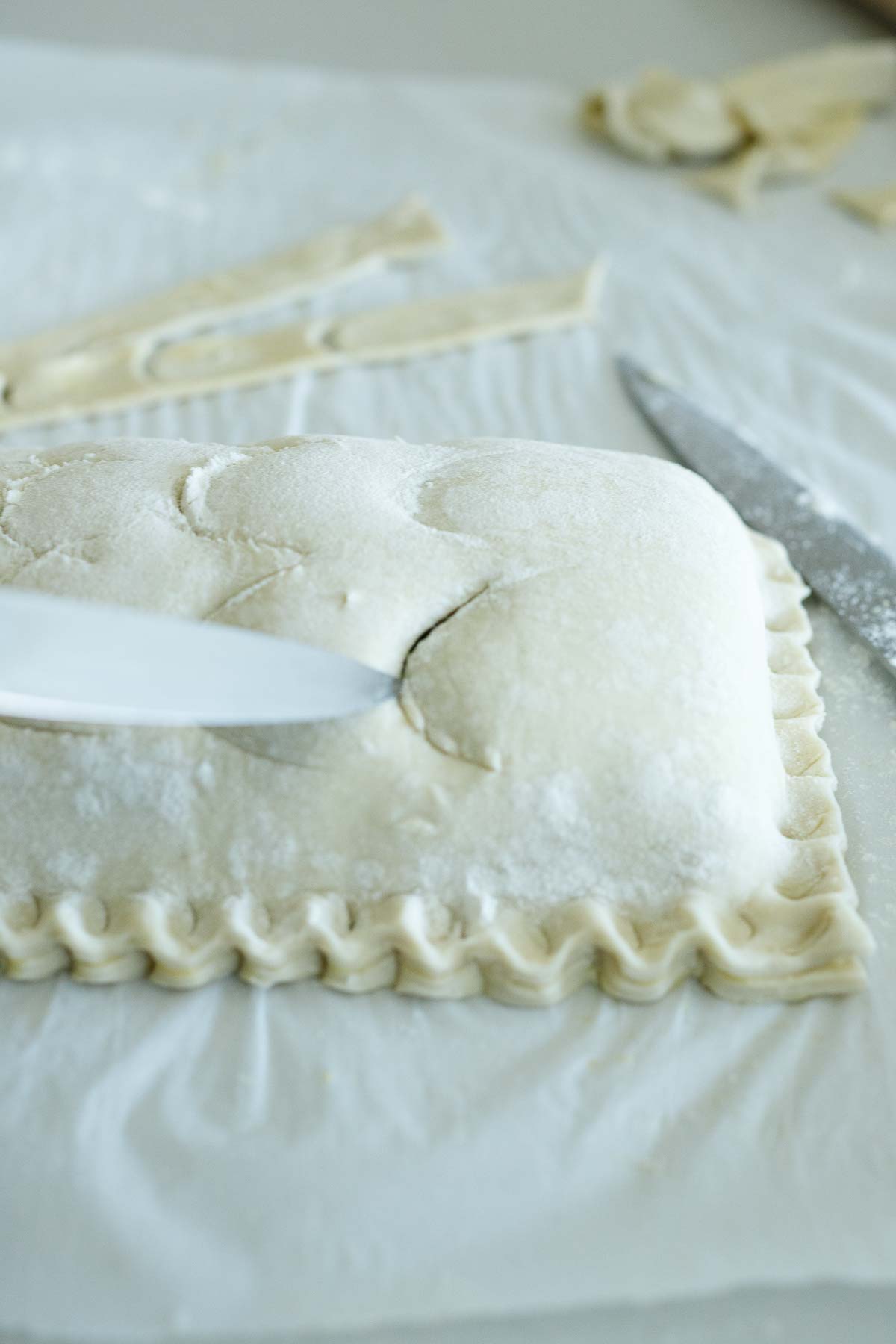 paring knife cutting into the fish scales on the puff pastry.