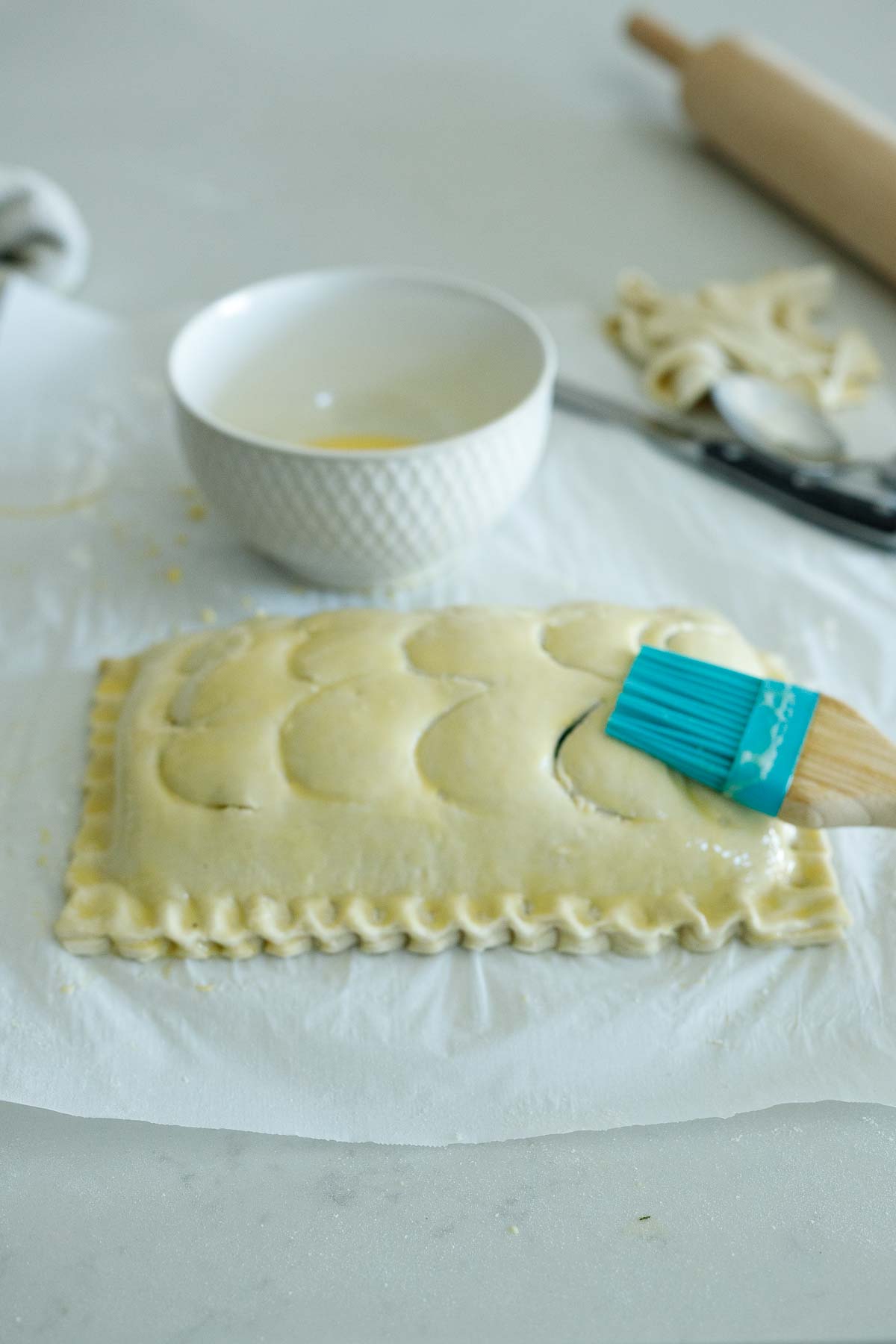 brushing egg wash over top of the puff pastry of the salmon wellington.