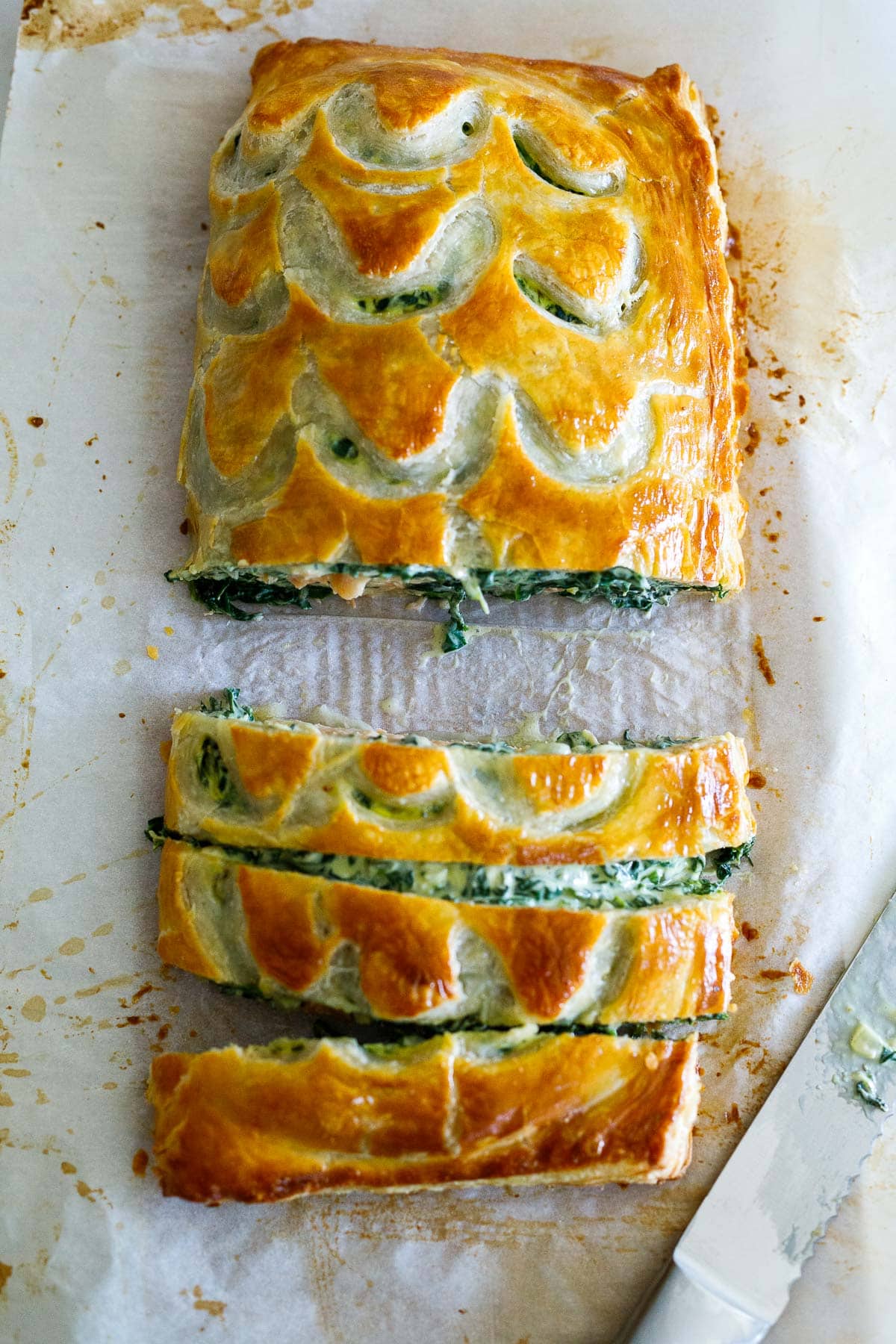 baked salmon wellington on parchment, cut into slices. 