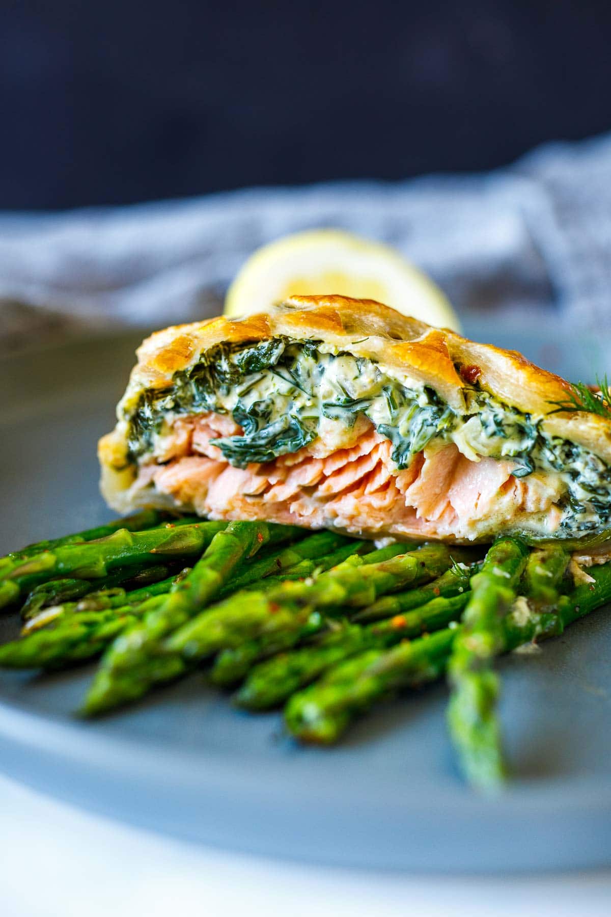 slice of salmon wellington with creamy spinach filling and flaky salmon, served on top of roasted asparagus. 