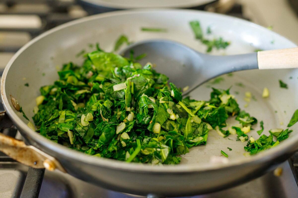 sautéing spinach in skillet with garlic and shallot.