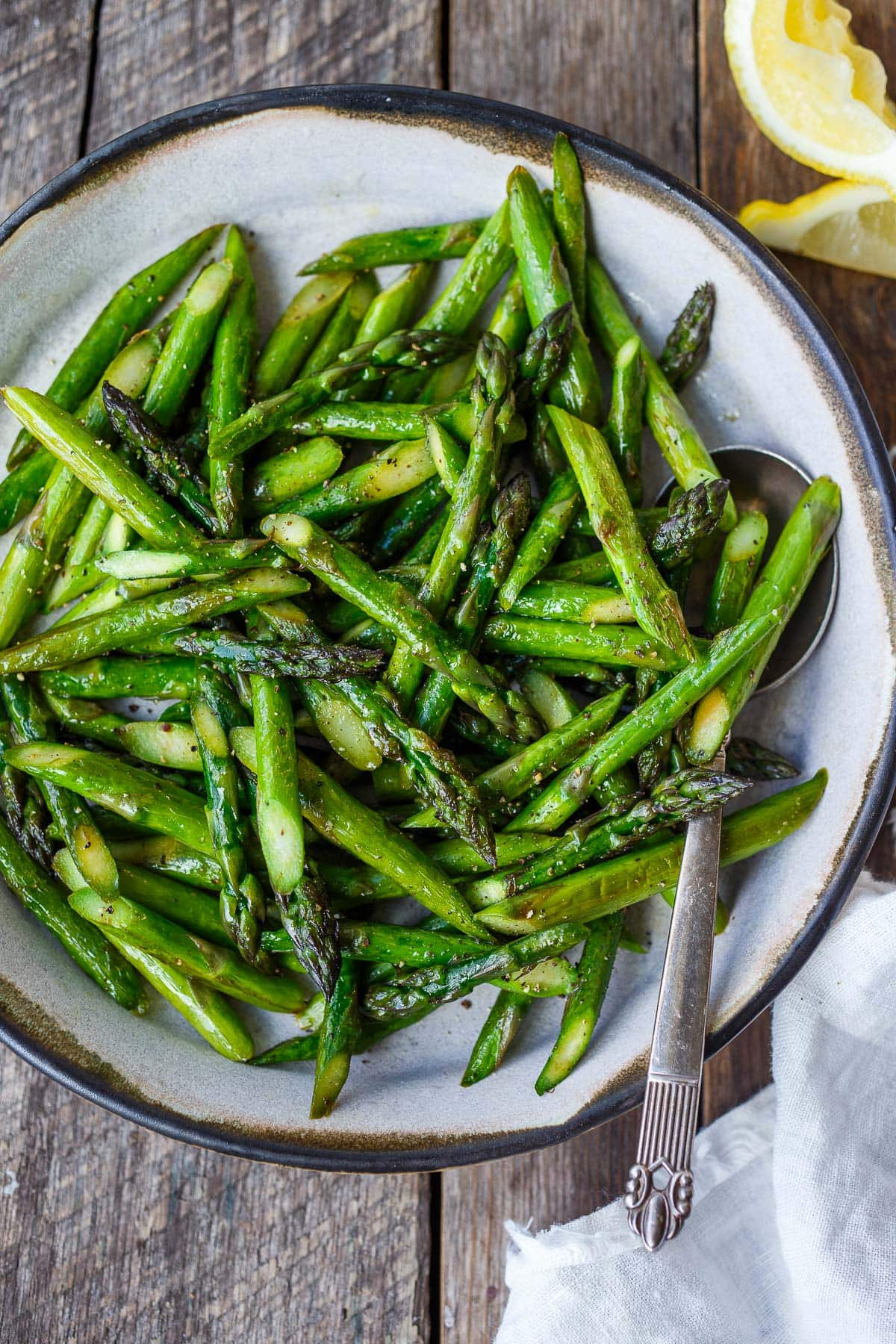 serving dish with sauteed asparagus with salt and pepper.