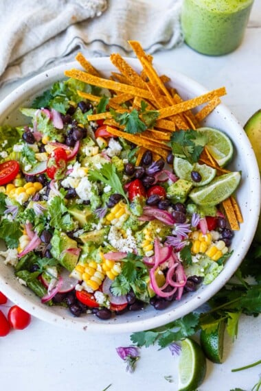 This vegetarian taco salad recipe is healthy and easy-made w/ black beans, tomatoes, corn, avocado, crisp romaine & zesty cilantro lime dressing.