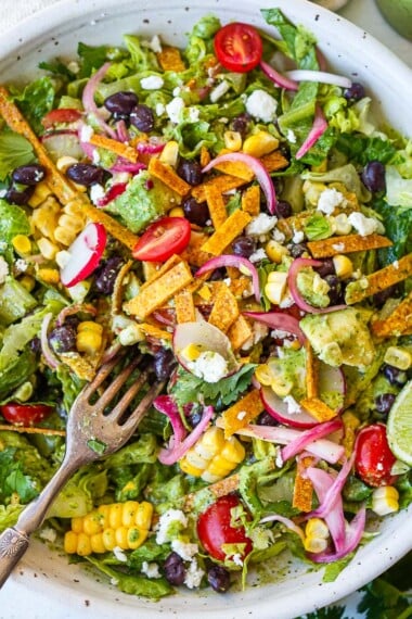 This vegetarian Taco Salad recipe is so tasty! It's easy and flavorful, made with black beans, tomatoes, avocado, and crisp romaine with a zesty, creamy cilantro lime dressing. Gluten-free and vegan-adaptable.