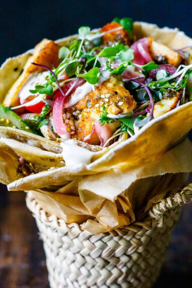 A delicious Halloumi Wrap recipe made with flavorful manoushe, pan-seared halloumi, fresh veggies, and a creamy tahini yogurt sauce.