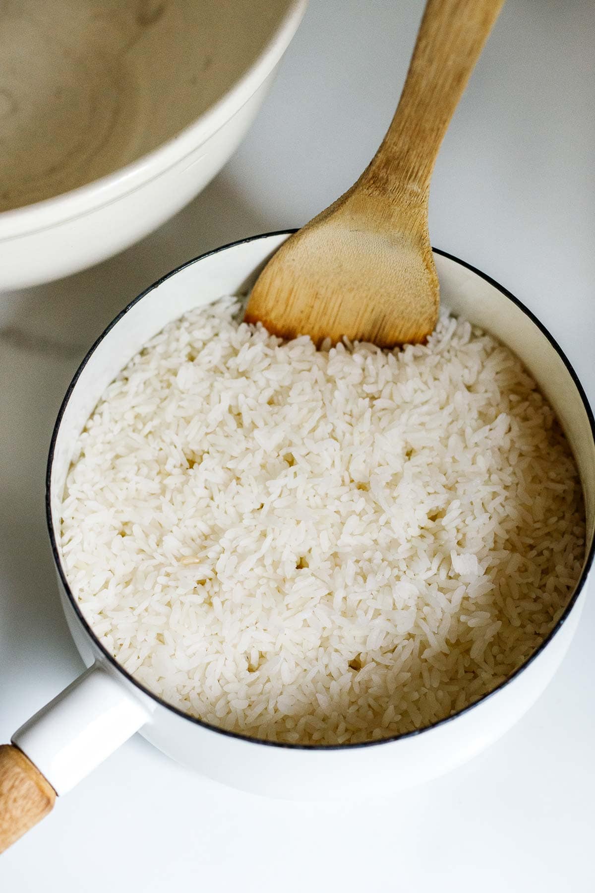 cooked sushi rice in pot with wooden paddle.