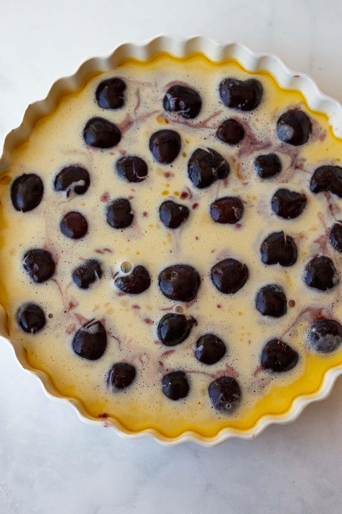 unbaked cherry clafoutis in round baking dish.