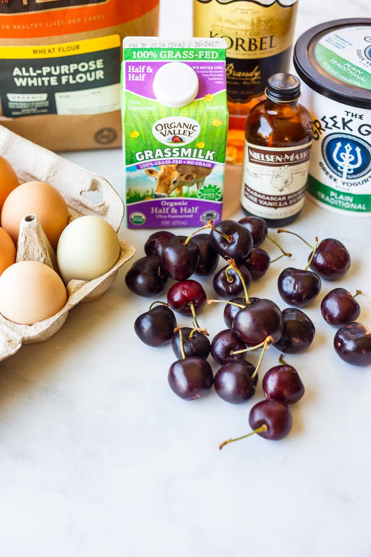 ingredients for cherry clafoutis - eggs, half and half, fresh cherries, vanilla extract, greek yogurt, brandy, all purpose flour.