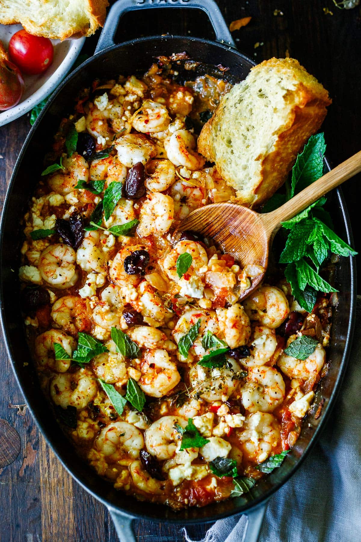 This Greek-inspired Shrimp Saganaki recipe is our new favorite! The shrimp is pan-seared and baked in a fresh tomato sauce with feta cheese, kalamata olives, lemon and mint. Serve it as a tasty appetizer or weeknight dinner!