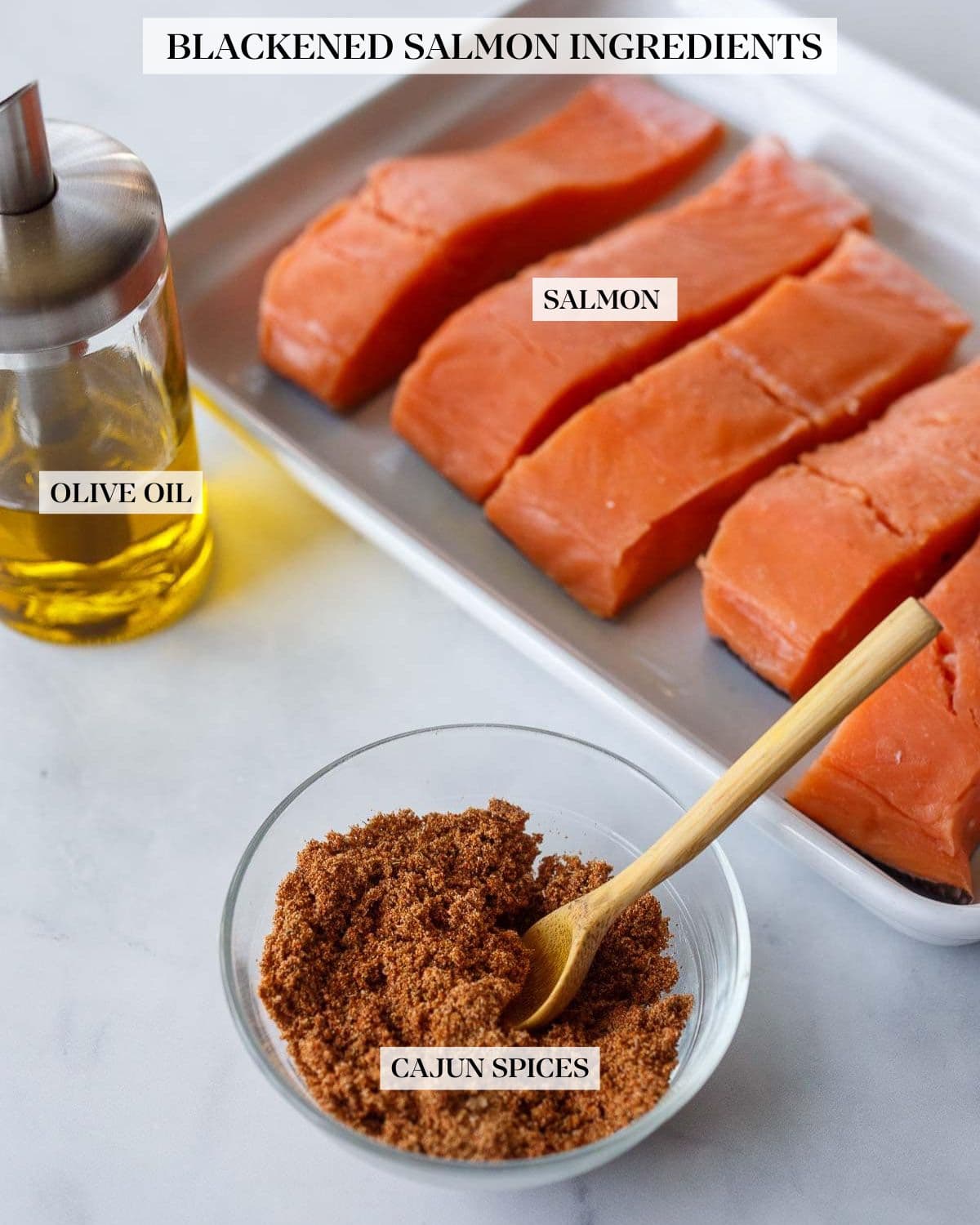 salmon filets on tray next to olive oil and a small bowl of cajun seasoning.