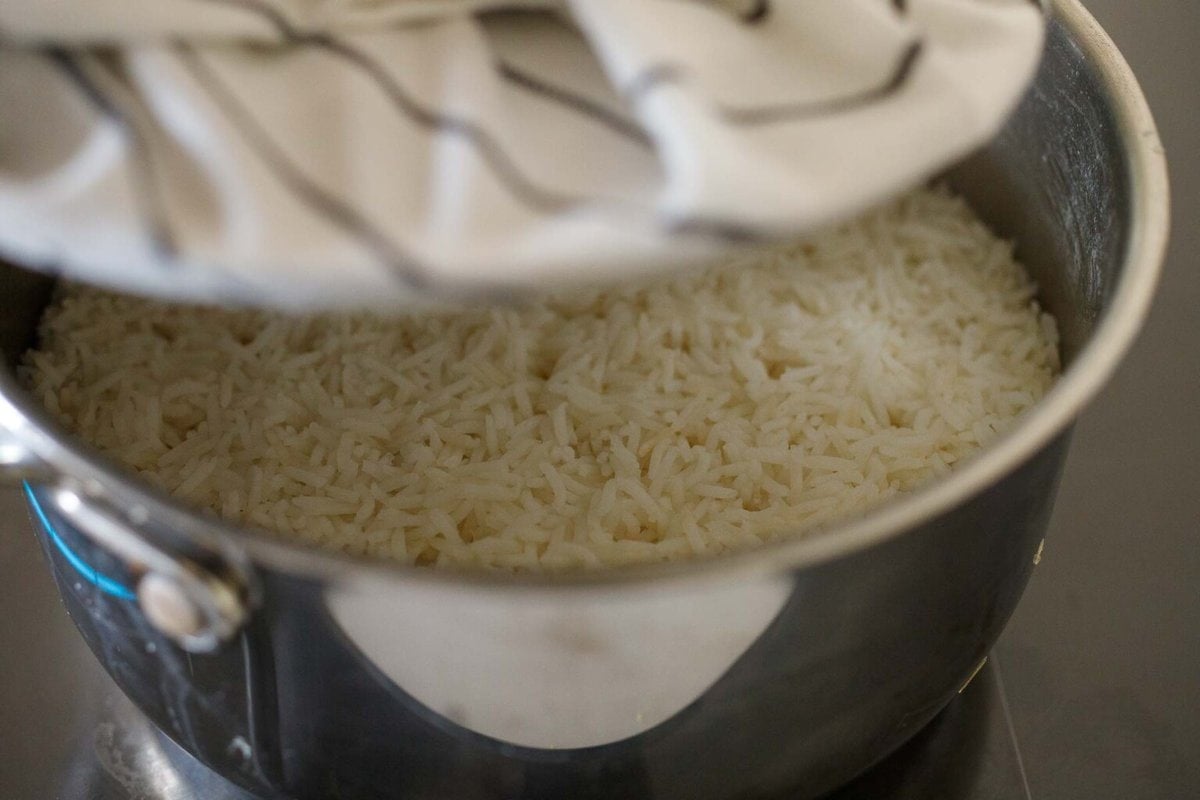 lifting lid off pot to see steamed basmati rice.