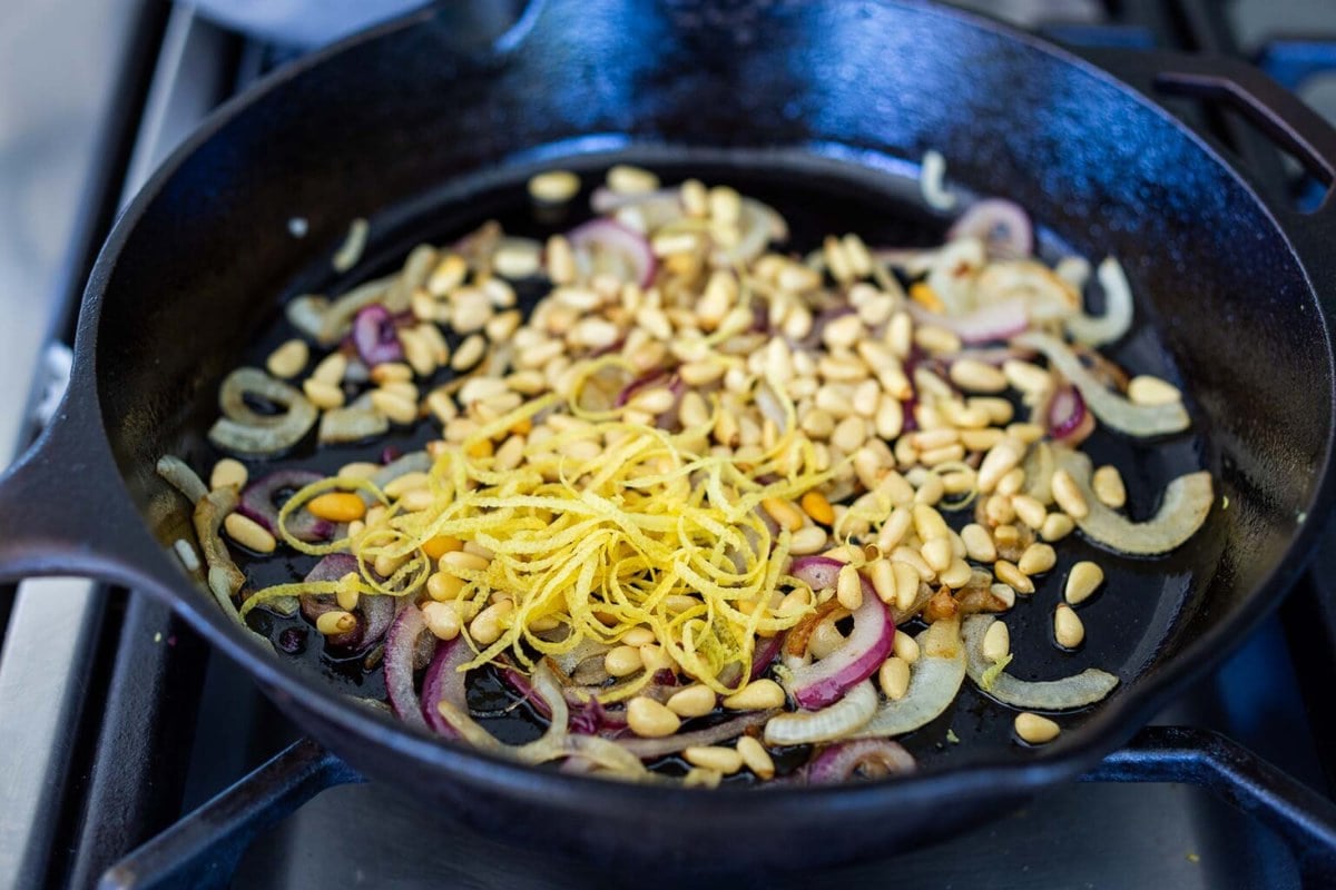 cast iron skillet with shallots, pine nuts, and lemon zest.