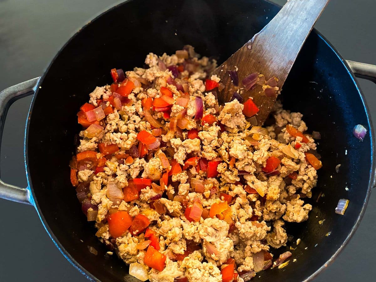 pot with cooked ground turkey and sautéed peppers and onions.