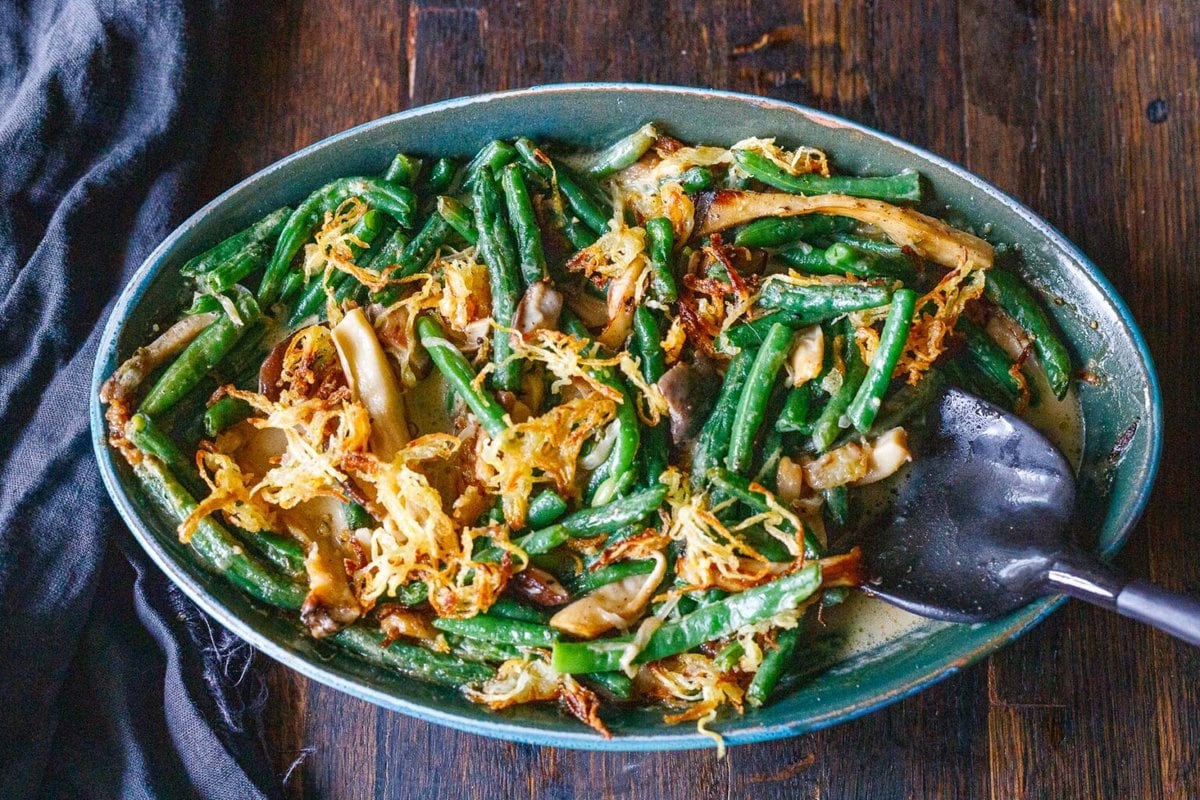 oval baking dish with green bean casserole topped with crispy onions. 