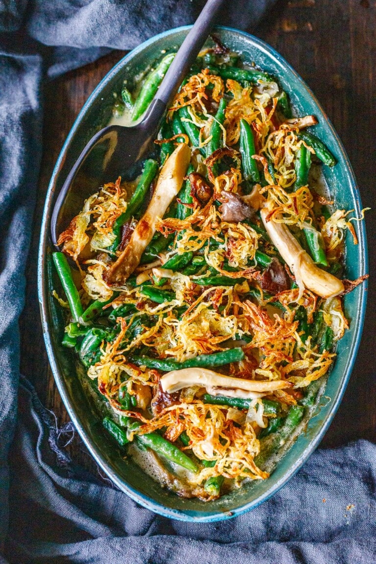 green bean casserole in oval baking dish with crispy onions and mushrooms.