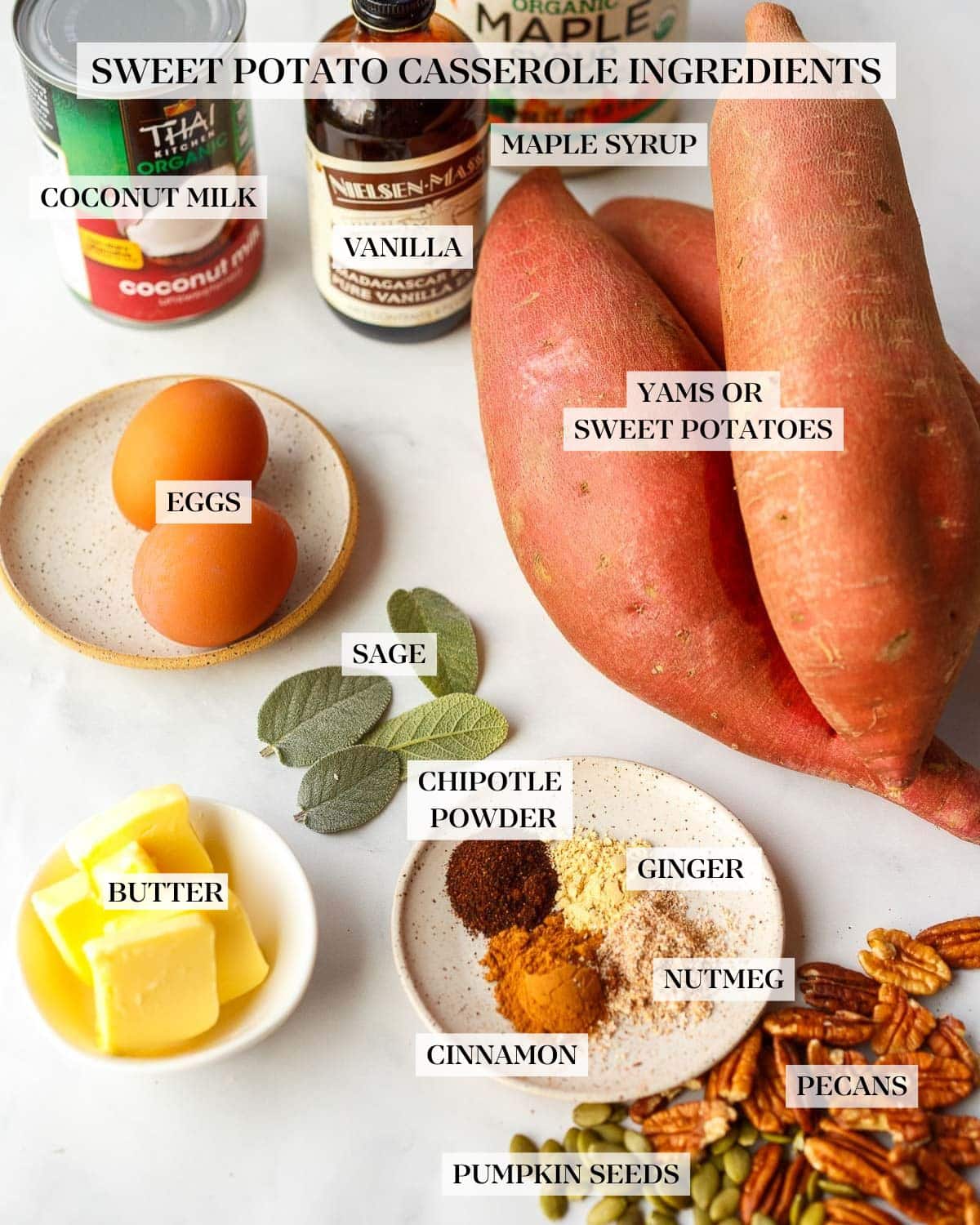 ingredients for sweet potato casserole - maple syrup, vanilla, coconut milk, eggs, sweet potatoes, sage leaves, butter, spices, pecans, pepitas.