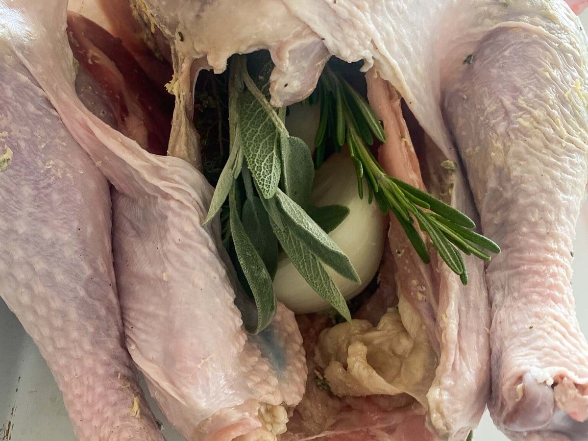 turkey with fresh herbs and onion placed in cavity. 