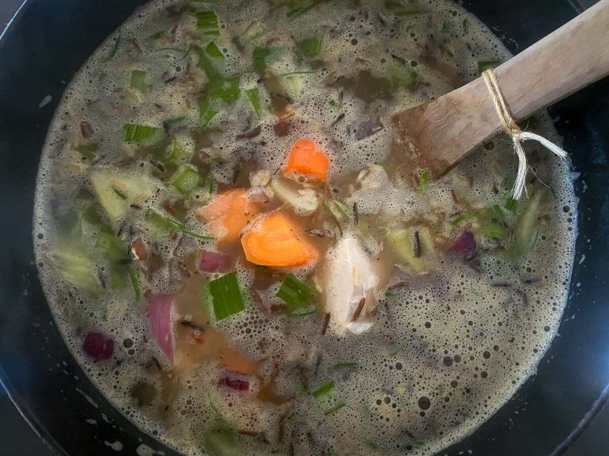 large pot with veggies, wild rice, and turkey broth.